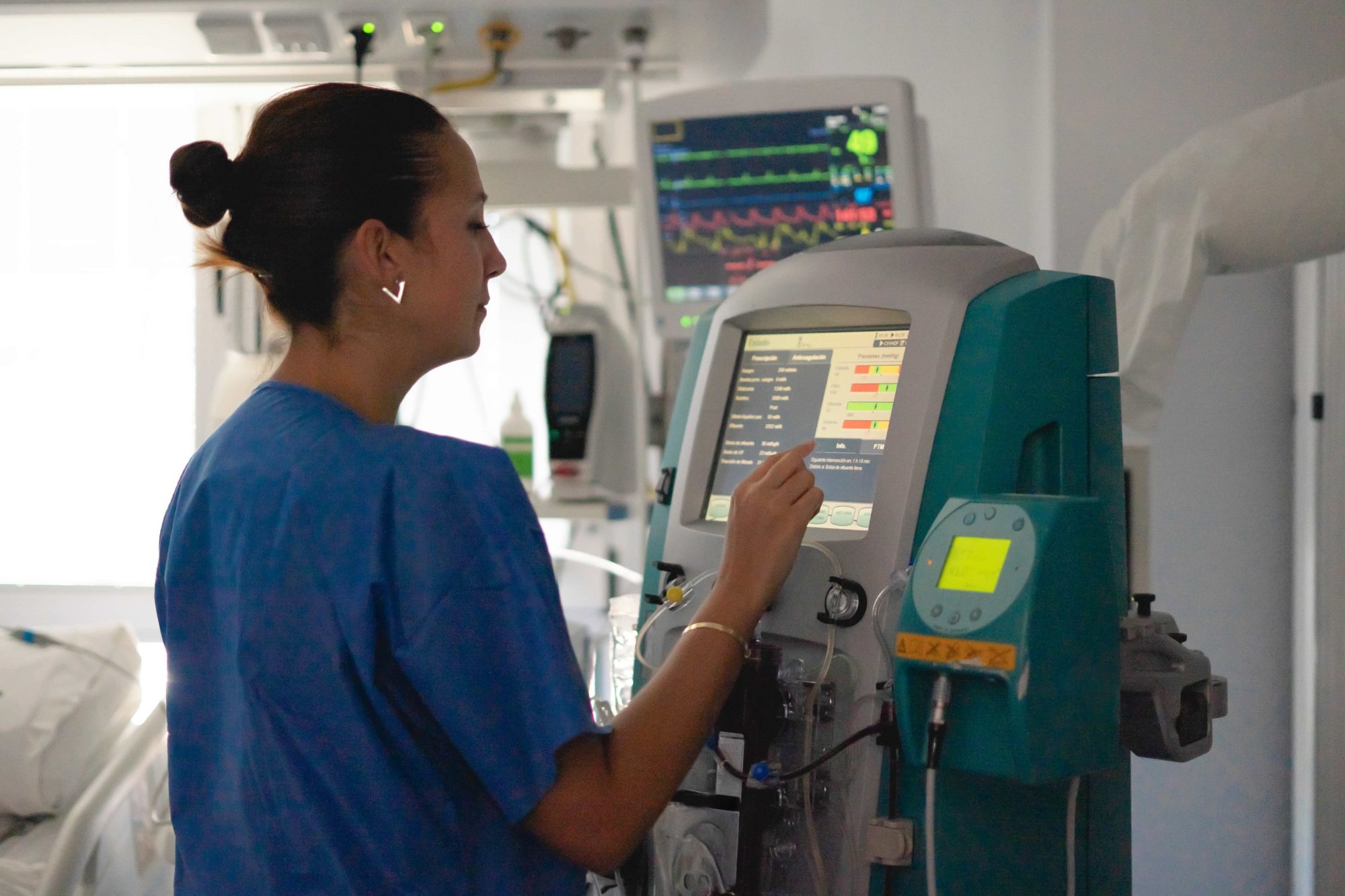 Nurse monitoring medical equipment, providing patient care in a clinic.